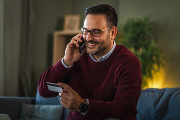 Man making secure online payment with smart phone and credit card at home