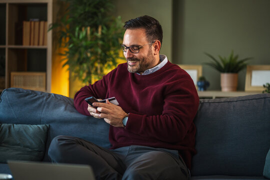 Man making secure online payment with smart phone and credit card at home - Powered by Adobe