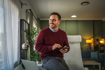 Smiling man working from home checking mobile phone
