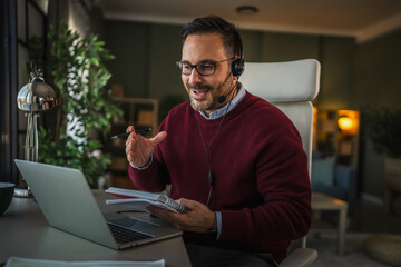 Man in headset having online video call from home office