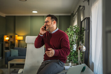 Man laughing while talking on phone working from home