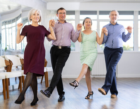 Elderly people with middle-aged man holding hands dancing hava nagila. Dance lessons for amateurs and beginners
