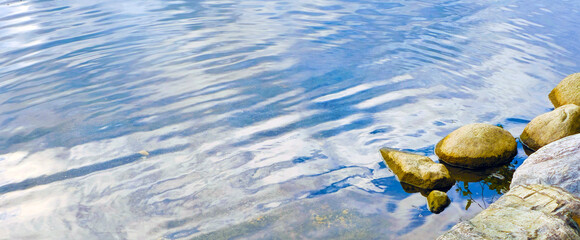 Soft Ripples of Blue Water Breaking at the Shoreline by Rocks