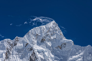 Cirrus clouds over the snowy Mt. Nuptse summit illuminated by sun. View from Kala Patthar mount on Everest base camp trek, Nepal.