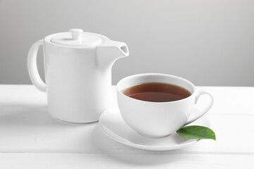 Hot tea in cup and teapot on white wooden table