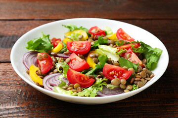 Delicious salad with lentils and vegetables on wooden table, closeup
