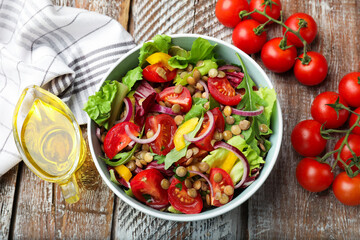 Delicious lentil salad, tomatoes and oil on wooden table, flat lay