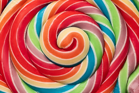 Colorful rainbow lollipop swirl on wooden stick as food color background