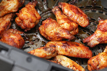 Grilled chicken wings on barbecue grill. Roasted spicy meat closeup. Golden brown crispy poultry pieces. Outdoor cooking food background. Juicy seasoned wings ready to eat.
