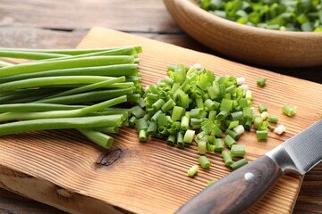 Cut green onions and knife on wooden table, closeup
