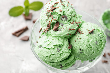 Tasty mint chocolate chip ice cream on grey textured table, closeup
