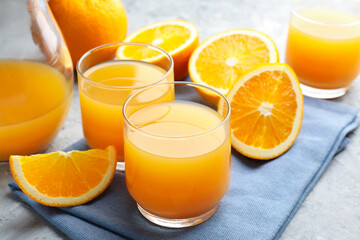 Fresh orange juice and fruits on grey table, closeup