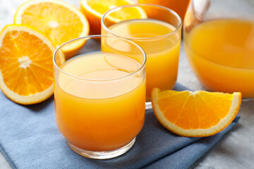 Fresh orange juice and fruits on grey table, closeup
