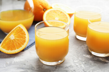 Fresh orange juice and fruits on grey table, closeup