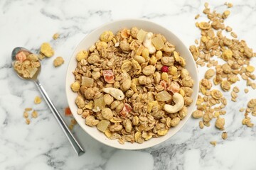 Tasty granola with dried fruits and nuts in bowl on white marble table, flat lay