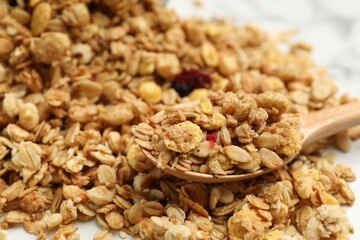 Tasty granola and spoon on white table, closeup