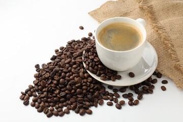 Fototapeta premium Cup of aromatic coffee and roasted beans on white background