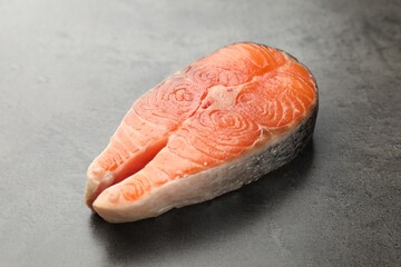 Piece of salmon fillet on gray textured table, closeup