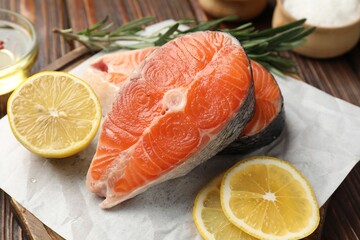 Pieces of salmon fillet with spices and lemon on table, closeup