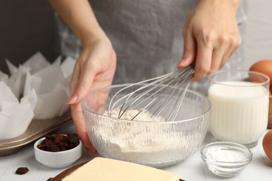 Woman whisking dough for muffins at white table, closeup