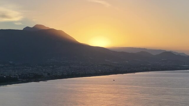 The stunning vista of a golden sunset casting hues over majestic mountains and a shimmering sea creates a tranquil atmosphere, perfect for nature lovers and sunset chasers alike, oe01