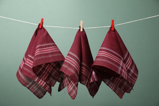 Beautiful cotton handkerchiefs hanging on string against olive background