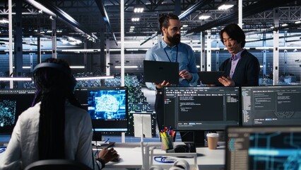 Data center manager supervising work done by programmers working on neural network software. Server hub supervisor overseeing IT staff members implementing deep learning tech, camera A