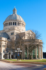Obraz premium Historic domed church building with columns and bare trees in front, viewed from a Christian science plaza in Boston on a clear blue sky day.