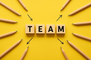 Vibrant yellow background showcases word TEAM spelled out with wooden blocks, surrounded by pencils pointing towards, symbolizing unity and collaboration. Collective effort, teamwork and cooperation