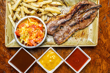 Juicy Grilled Beef Steak with Sear Marks Served with French Fries and Fresh Salad on Rustic Ceramic Plate