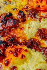 Close-up of a slice of pizza with crispy pork rinds, ripe plantain, shredded beef, chorizo sausage, and guacamole.