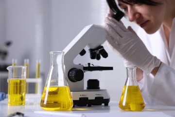 Scientist checking motor oil quality at table in laboratory, closeup. Space for text