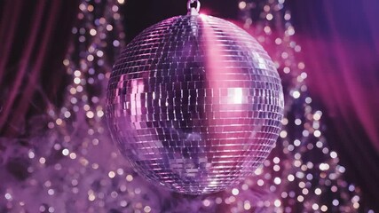 A dazzling disco ball hangs suspended reflecting vibrant pink and purple lights across a dark festive backdrop creating a sparkling and energetic atmosphere perfect for parties celebrations and retro. - Powered by Adobe