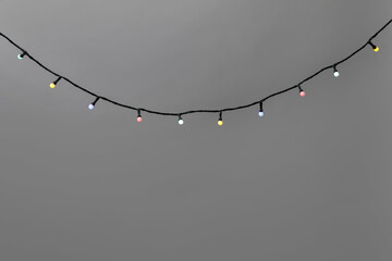 Bright Christmas lights on gray background, closeup. Space for text