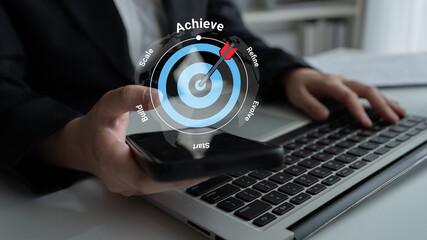 A business professional holds a smartphone while working on a laptop, with a focus on an overlay concept of achievement targets for effective strategic planning. Gantry