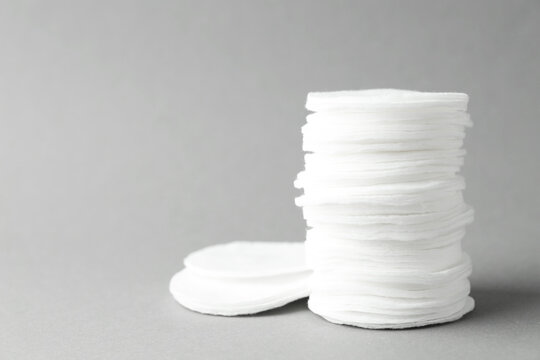 Stack of clean cotton pads on light grey background, closeup. Space for text