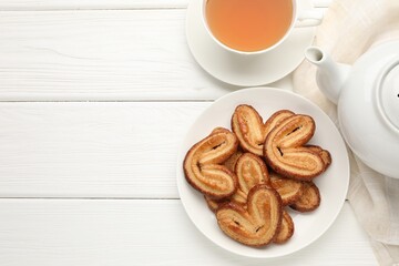 Yummy palmier cookies served with tea on white wooden table, flat lay. Space for text