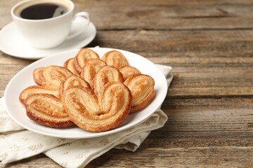 Yummy palmier cookies served with coffee on wooden table, closeup. Space for text