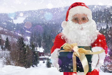 Santa Claus holding gift box under falling snow in mountains