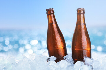Bottles of beer in ice near sea. Refreshing summer drink