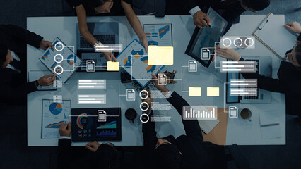 A diverse team engages in a collaborative business meeting with laptops and data charts, discussing strategies and insights in a modern office setting. Gantry