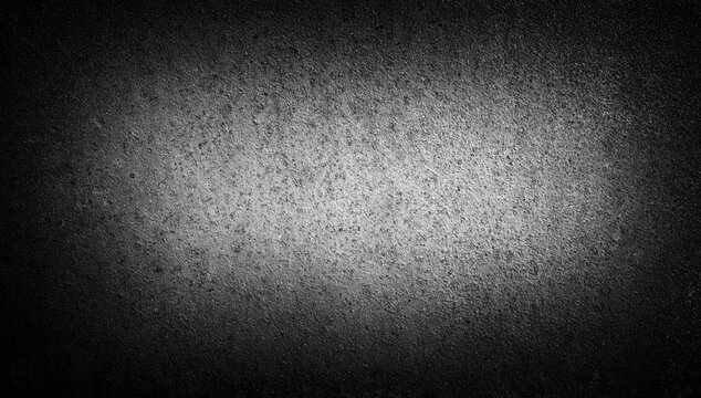 Dark concrete texture background with soft vignette light in the center. Rough matte surface with subtle grain and gradient shadows. Minimal abstract backdrop suitable for banners, posters
