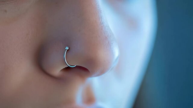 Woman applying vibrant eyeshadow, her nose pierced, creating expressive eye makeup with a unique style.