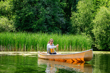 A man paddles a canoe through quiet wetlands on the Toronto Islands, surrounded by tall reeds and dense greenery, enjoying calm summer waters and outdoor leisure.