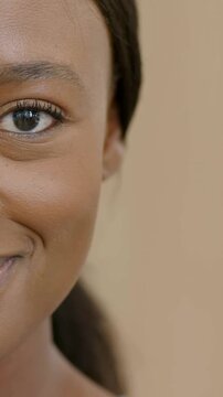 Vertical video: Smiling woman with hair tied back responding to camera, widening smile at studio