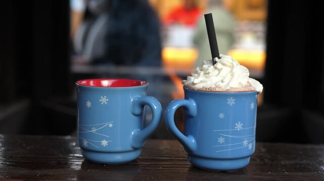 Cozy winter scene with two mugs of hot chocolate topped with whipped cream. Warm drink concept, hygge lifestyle, comfort, relaxation, and seasonal winter mood