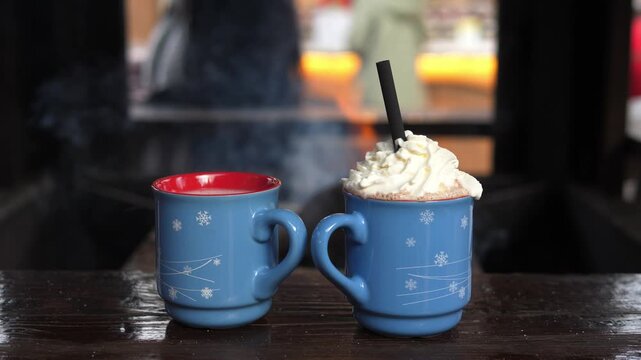 Cozy winter scene with two mugs of hot chocolate topped with whipped cream. Warm drink concept, hygge lifestyle, comfort, relaxation, and seasonal winter mood