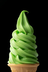 黒背景に浮かぶ抹茶ソフトクリームコーンの緑色スイーツ