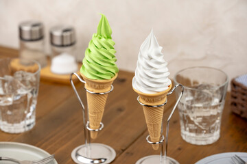 カフェテーブルの抹茶とバニラのソフトクリームコーン二つと金属スタンド