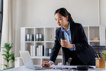 Business financial documents Asian woman Asian manager working with laptop and financial documents, sitting at her desk in modern office, analyzing data and preparing report
